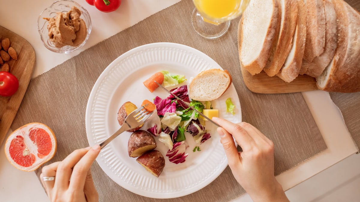 Top view of a nutritious breakfast setup with salad, bread, and fresh juice, perfect for a healthy start.