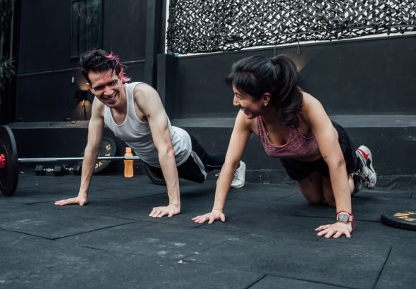 Man and woman doing pushups while smiling during a workout inside a Mexico City gym.
